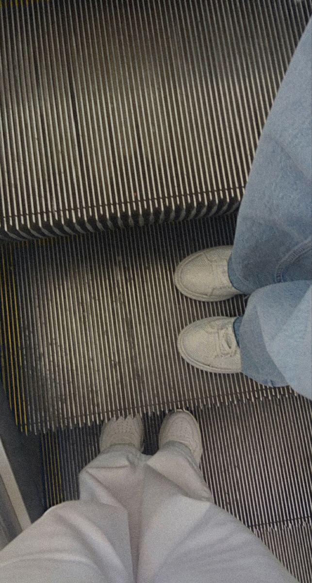 two people standing on an escalator next to each other with their feet up