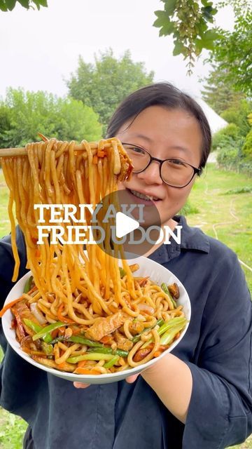 a woman holding a plate of noodles with the words teriya fried don on it