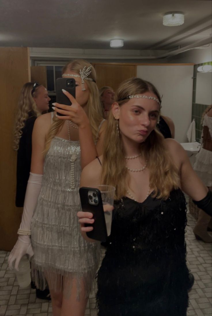 two women standing next to each other in front of a mirror with their cell phones