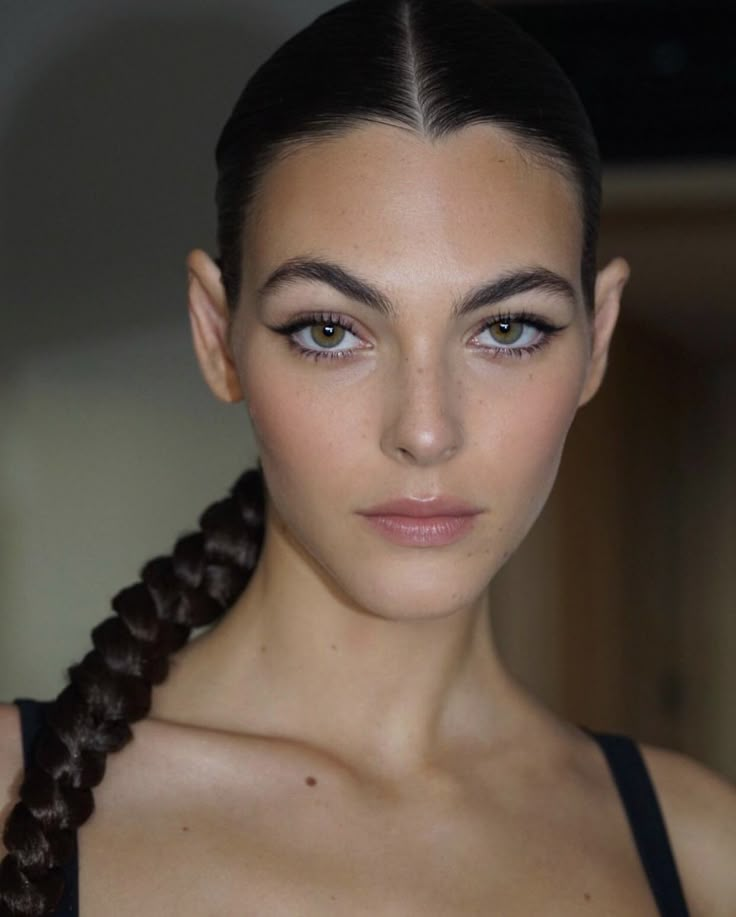 a woman with braids on her hair and blue eyeshade, wearing a black top