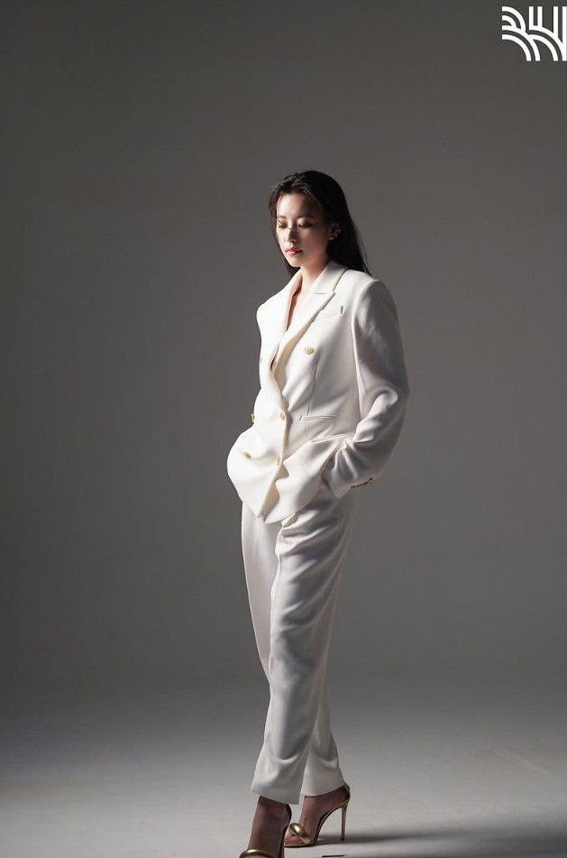 a woman in a white suit and heels posing for a magazine cover photo with her hands on her hips