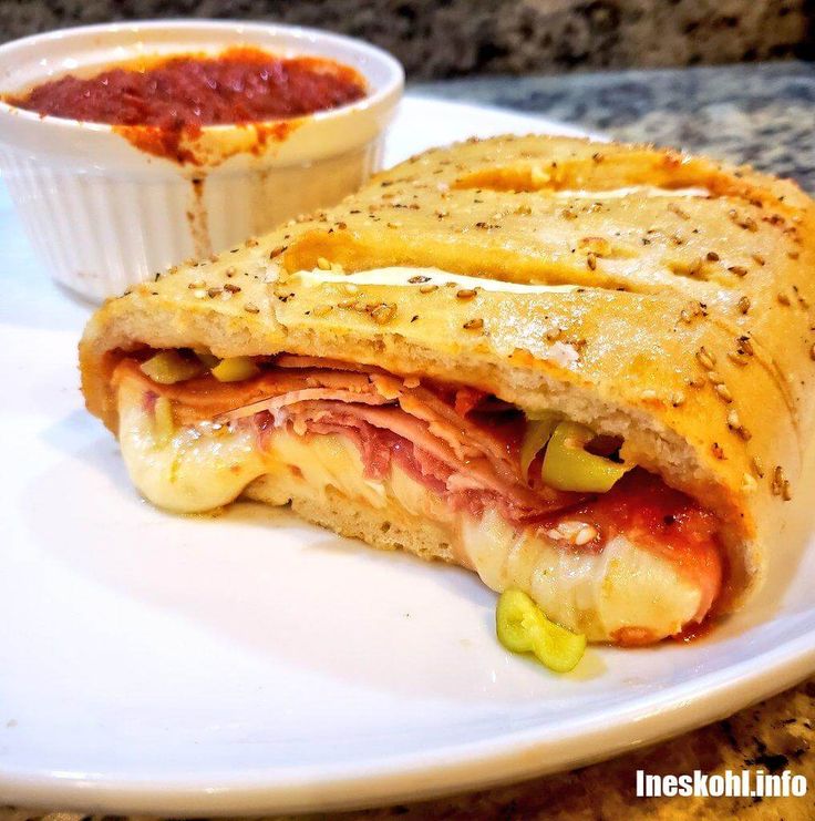 a white plate topped with a cut in half sandwich next to a bowl of salsa