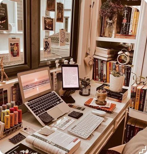 a laptop computer sitting on top of a desk next to a book shelf filled with books