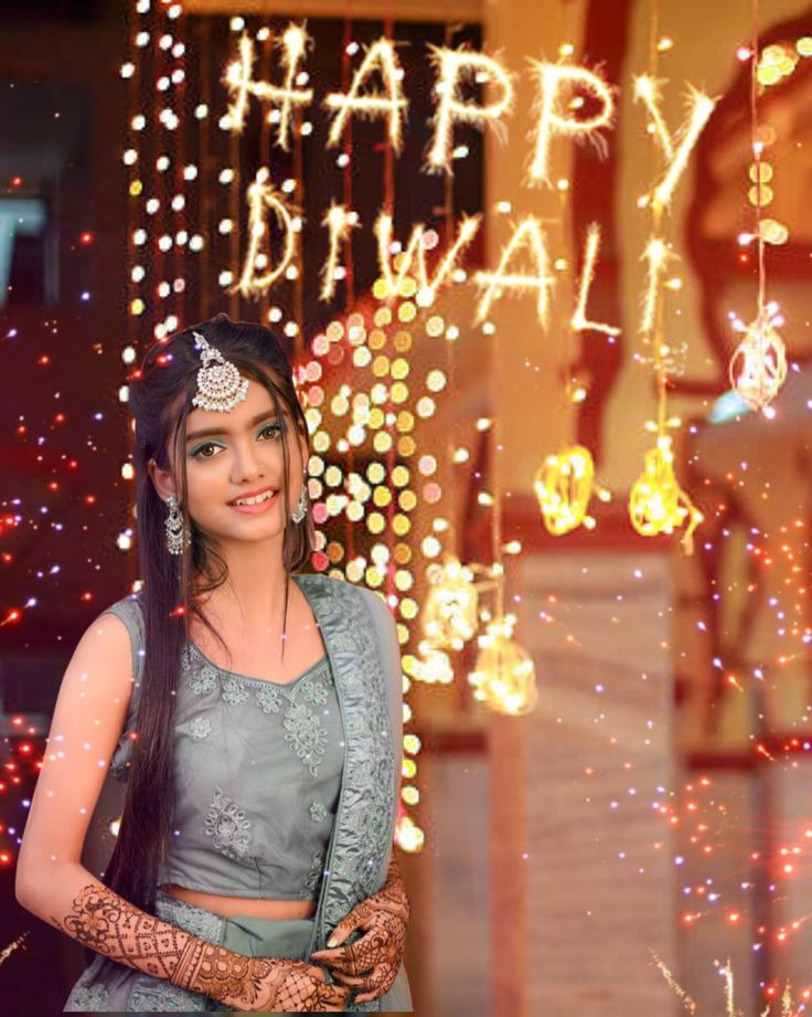 a woman standing in front of a happy diwali sign with lights on it