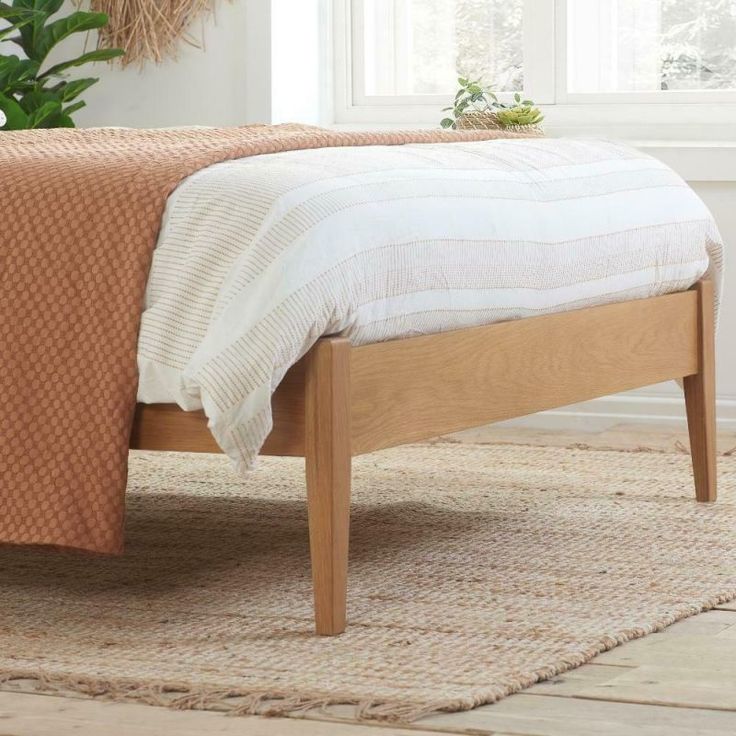 a bed sitting on top of a wooden floor next to a plant in a room