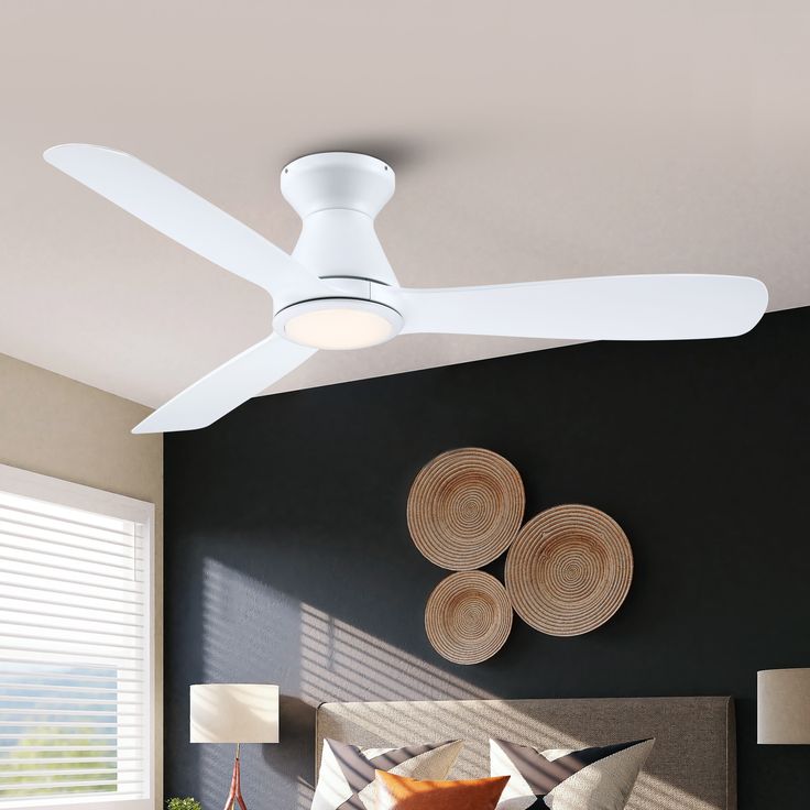 a white ceiling fan mounted on the side of a wall above a bed in a bedroom