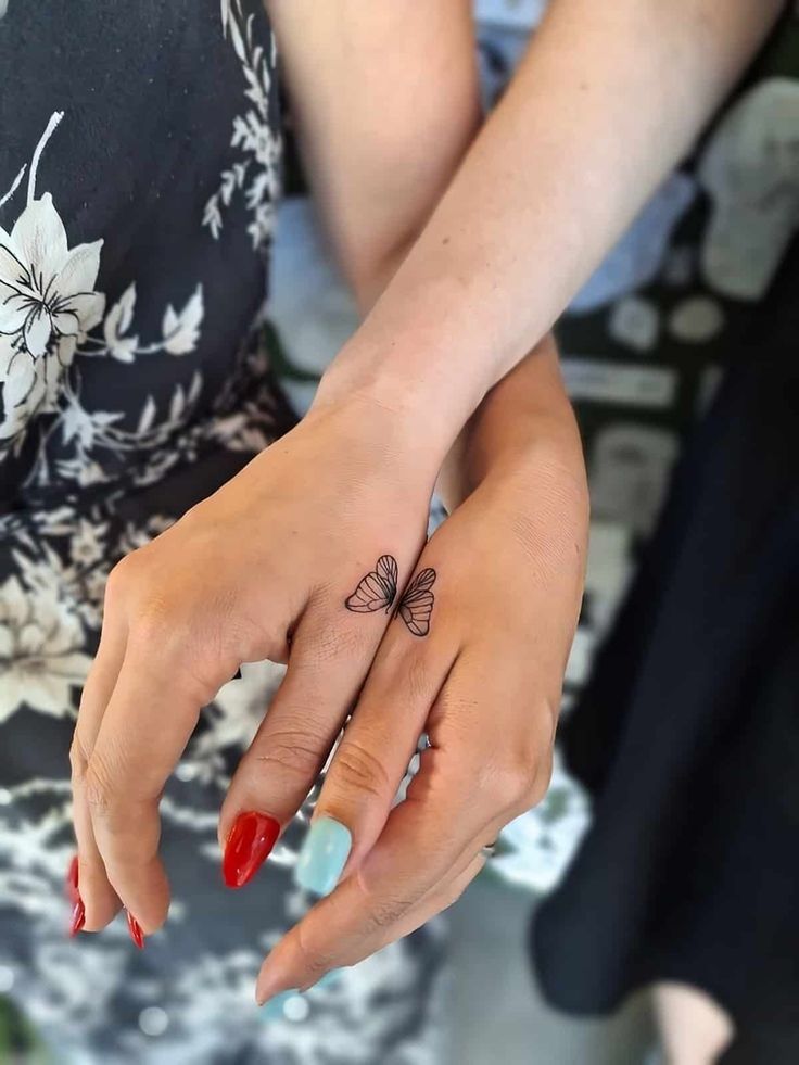 two women with matching tattoos on their hands and one has a butterfly tattoo on her finger