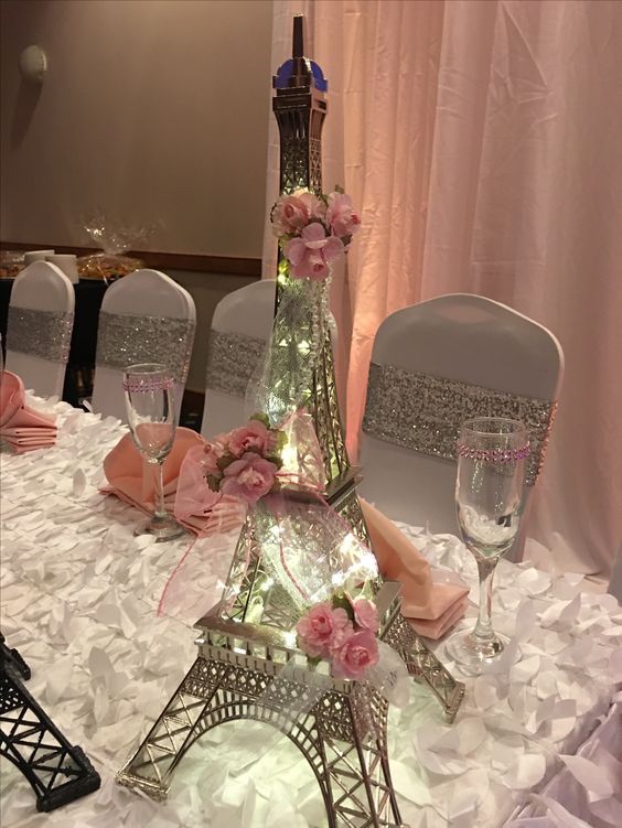 the eiffel tower is decorated with pink flowers and glass goblets for an elegant wedding reception