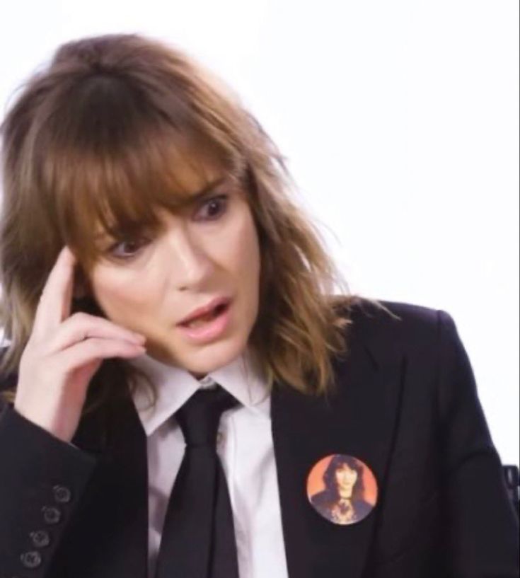 a woman in a suit and tie talking on the phone with her hand to her ear