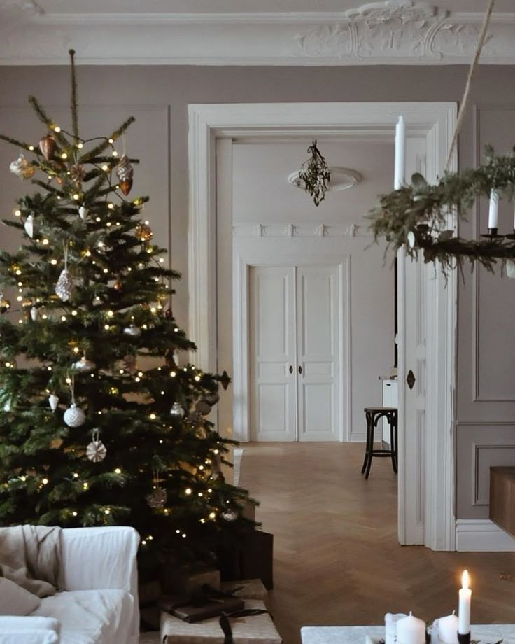 a living room with a christmas tree in the corner and candles on the coffee table