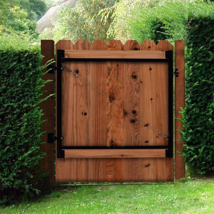 a wooden gate in the middle of some bushes