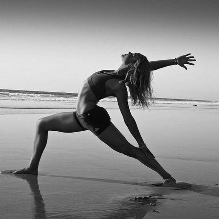 a woman is doing yoga on the beach