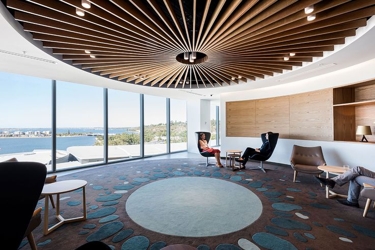 a living room filled with furniture and a large window covered in wood slat ceiling