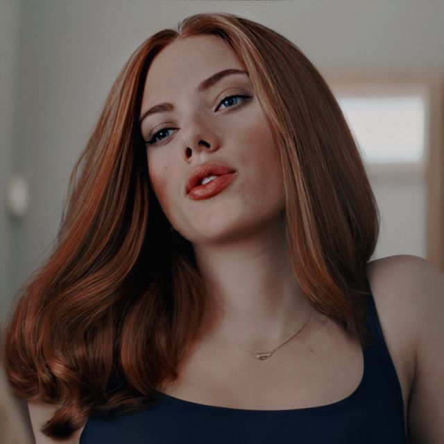 a woman with red hair and blue eyes is looking at the camera while wearing a black tank top