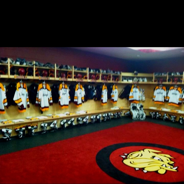 the hockey lockers are lined up with their jerseys on them and there is a rug in front of them