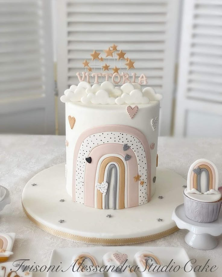 a white cake with pink and gold decorations on it's top is sitting on a table