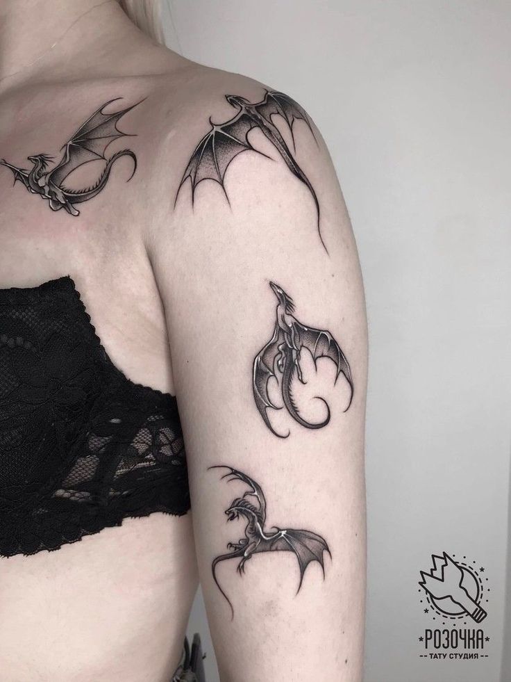 a woman's arm with tattoos on it, including two bats and one demon