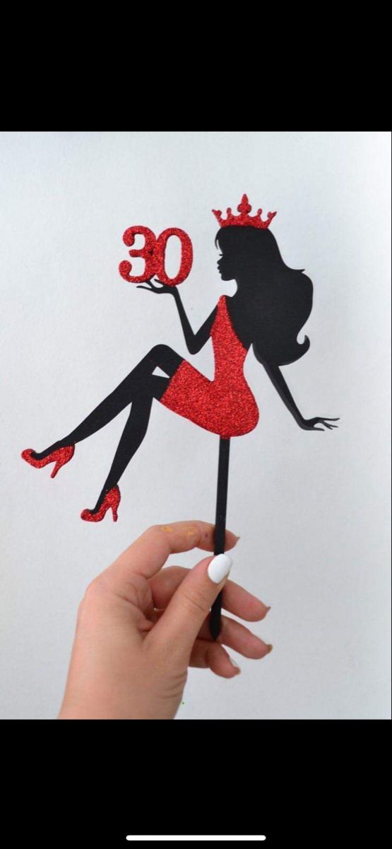 a woman holding up a cake topper with the number 30 on it's side