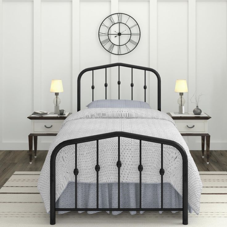 a black metal bed frame in a white room with two nightstands and a clock on the wall