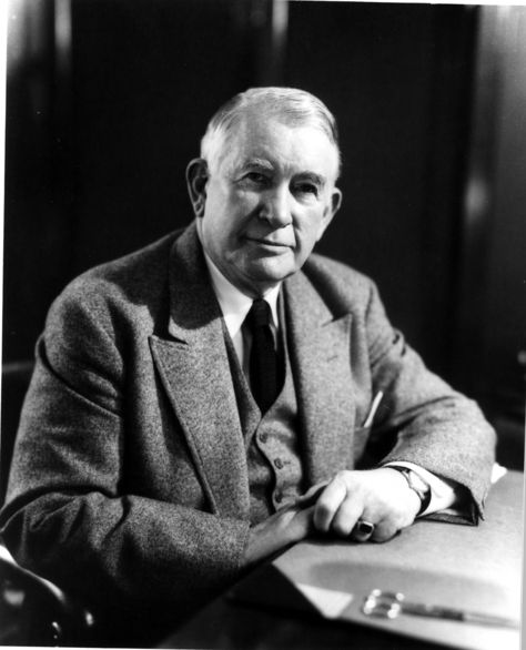 an old black and white photo of a man in a suit sitting at a desk