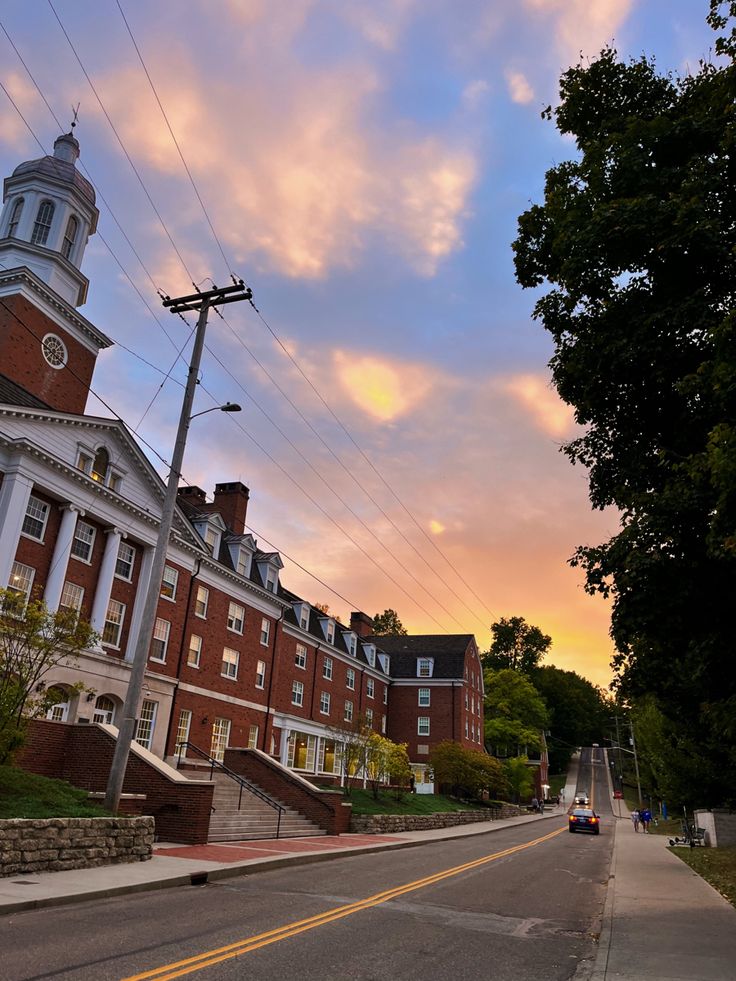 an old brick building with a steeple and clock on the top is shown at sunset