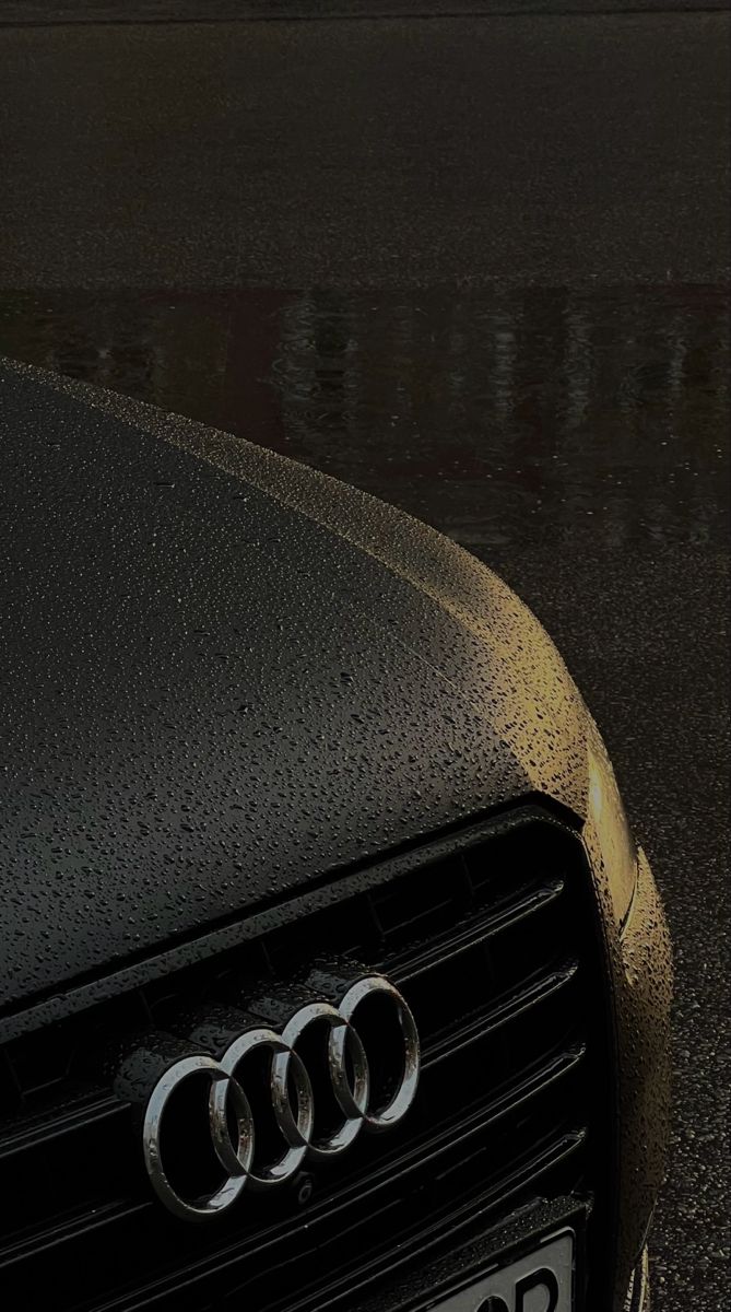 the front end of an audi car with rain drops on it