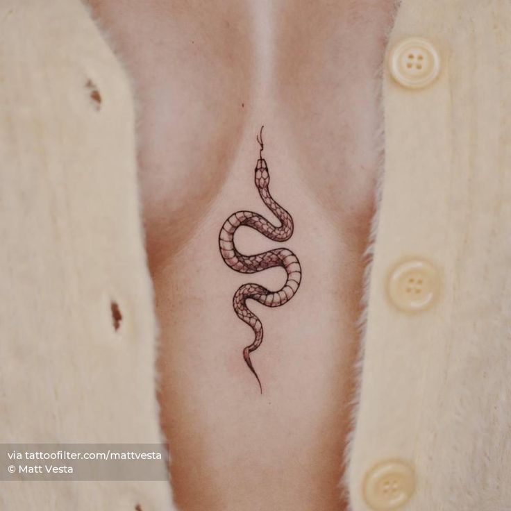 a woman's chest with a snake tattoo on her left side ribcage