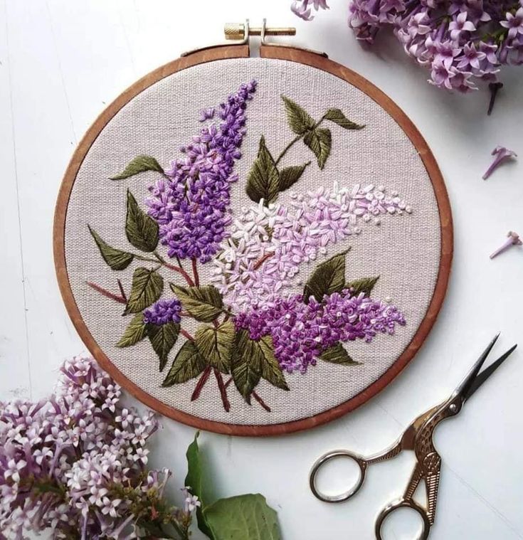 a close up of a embroidery on a table with scissors and flowers