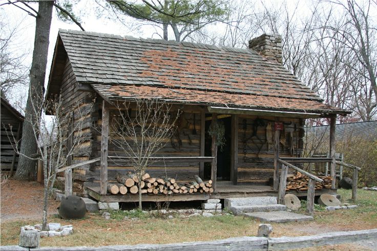 an old log cabin with logs stacked outside