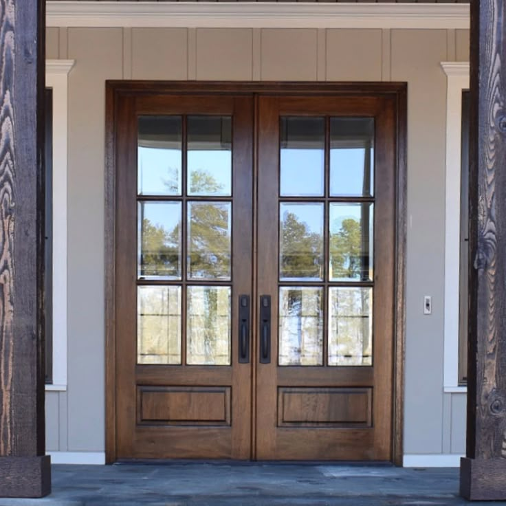 two wooden doors with glass on the front of a house in an open entry way