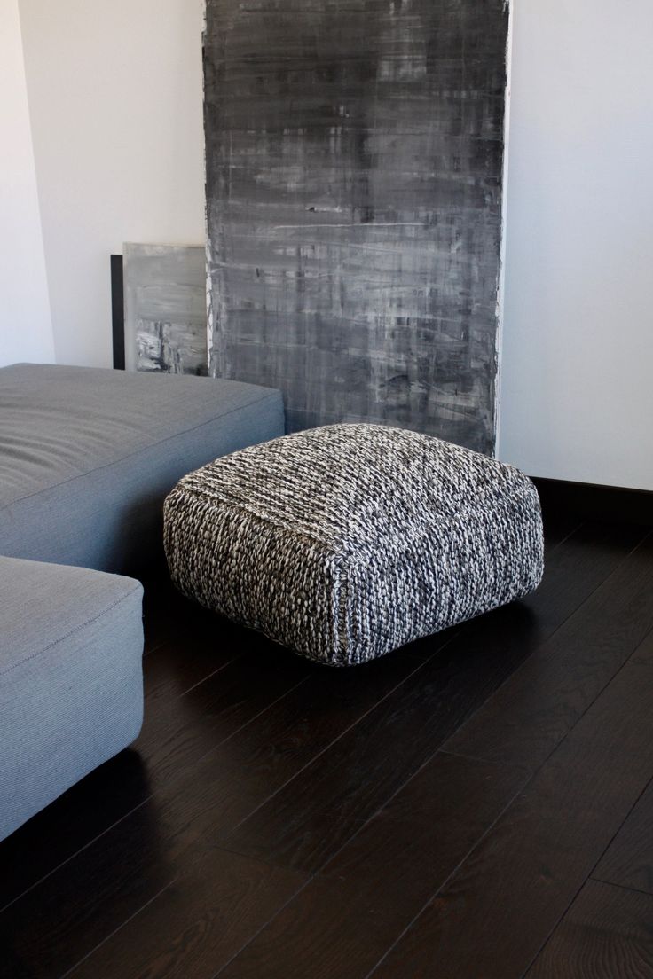 a living room with two gray couches next to a black and white painting on the wall