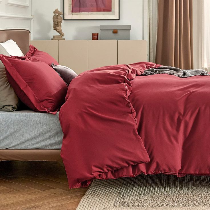 a bed with red sheets and pillows in a room