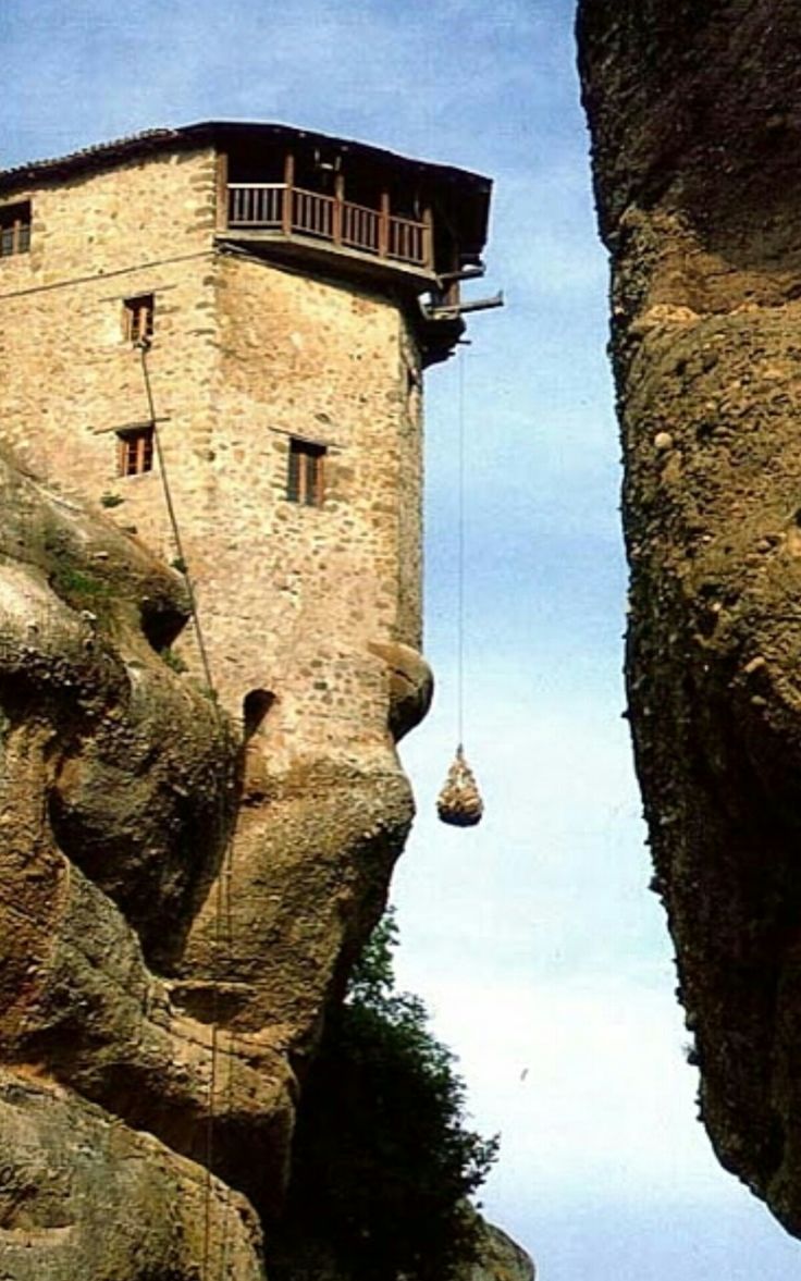 an old building on top of a cliff with a rope hanging from it's side