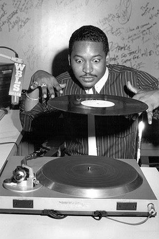 a man sitting in front of a record player with his hand on top of the record