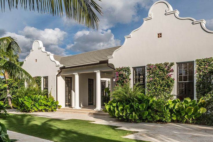 a white house surrounded by lush green plants