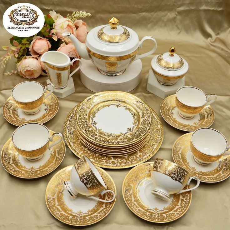 a table topped with lots of gold and white plates covered in fancy cups and saucers