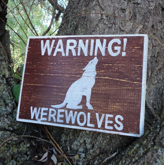 a wooden sign that says warning werewolvess on it, sitting in front of a tree