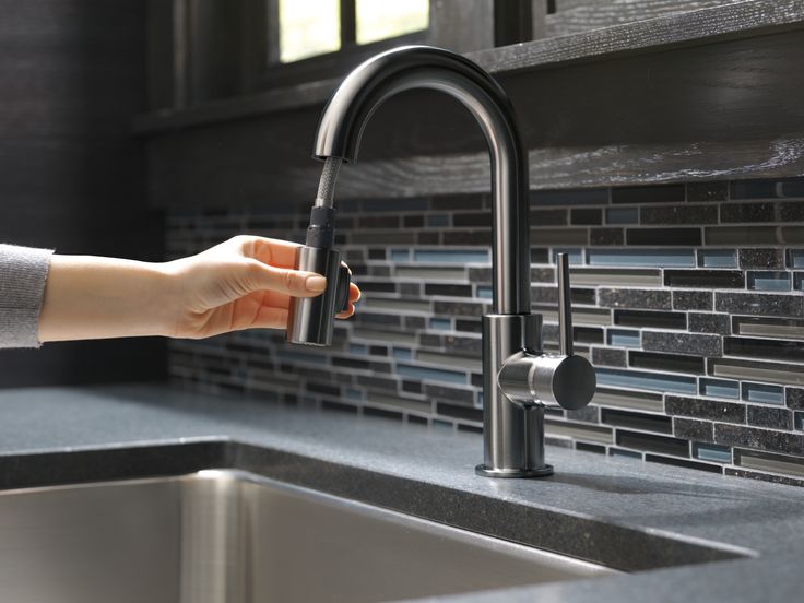 a woman's hand is holding onto the faucet in this kitchen sink