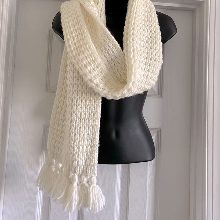 a white knitted scarf hanging on a mannequin's dummy in front of a door