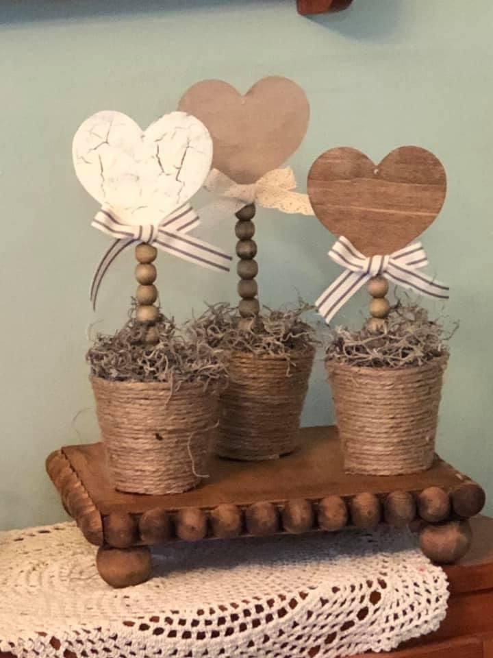 two wooden hearts are sitting on top of some straw and twine in small pots