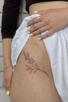 a woman's stomach with a small flower tattoo on her lower thigh and right leg