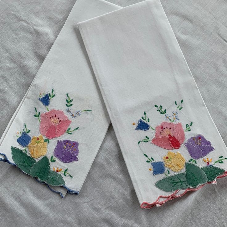 two white towels with embroidered flowers on them