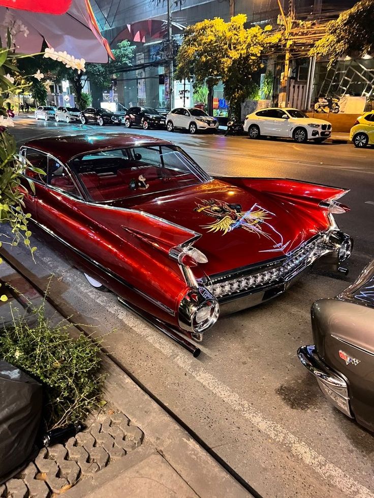 an old red car is parked on the side of the street