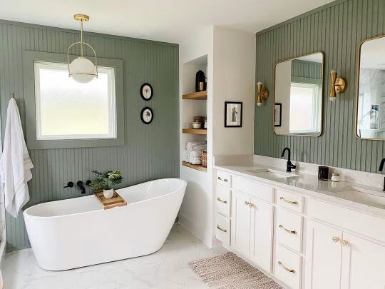 a white bath tub sitting under two mirrors in a bathroom