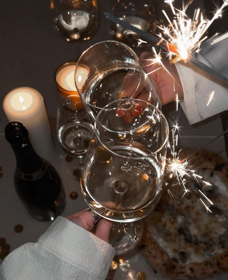 someone is toasting wine glasses with sparklers