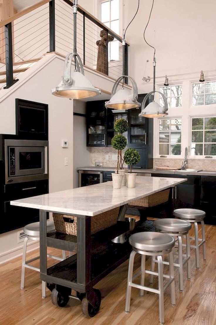 a kitchen island with stools and lights hanging from it's ceiling in front of an open floor plan