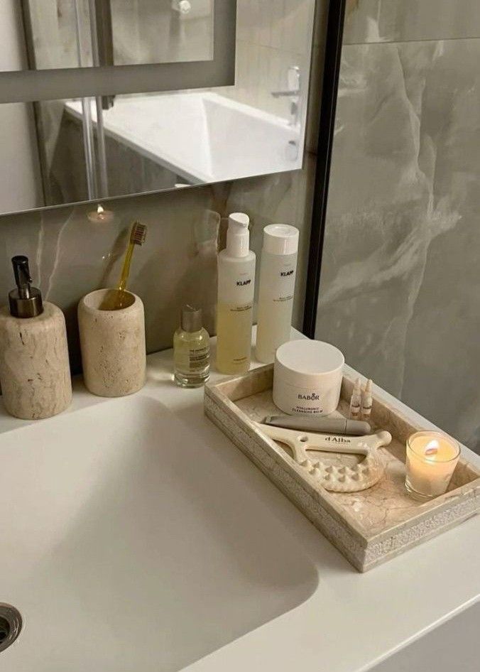 a bathroom sink with soap, lotion and candles sitting on the counter next to it