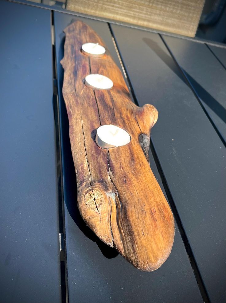 a piece of wood sitting on top of a black table next to three white lights