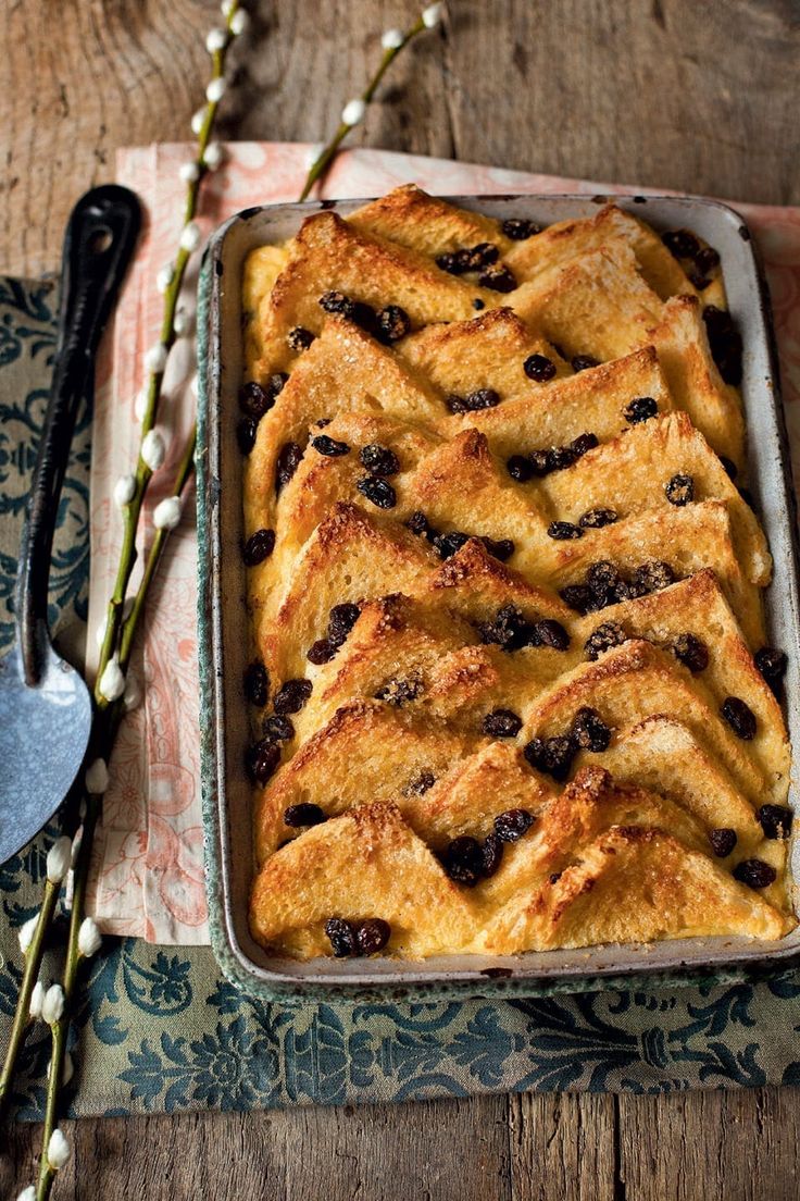 a pan filled with bread and blueberries on top of a table next to two forks