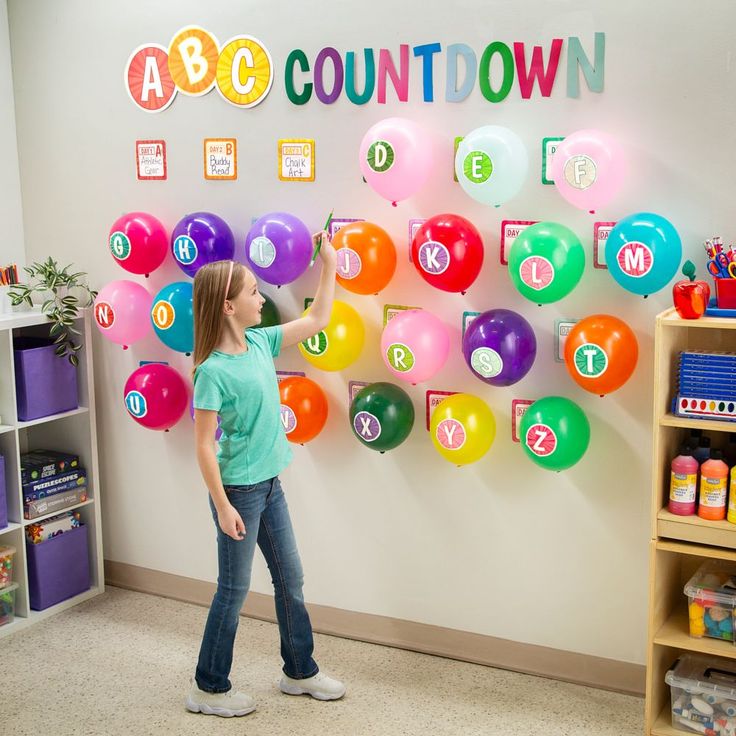 a girl standing in front of a wall with balloons on it